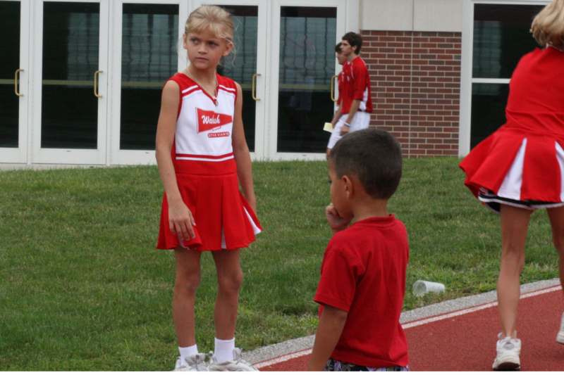 a girl in a cheerleader outfit standing on a track