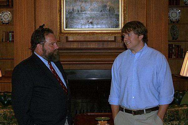 a man in a suit and tie standing next to another man in a room