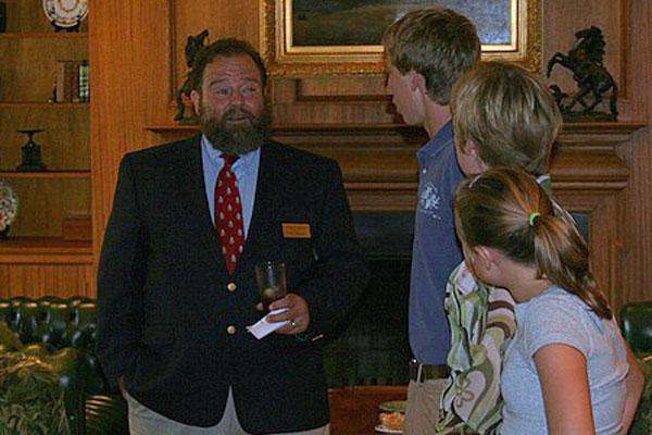 a man in a suit holding a glass and a group of people