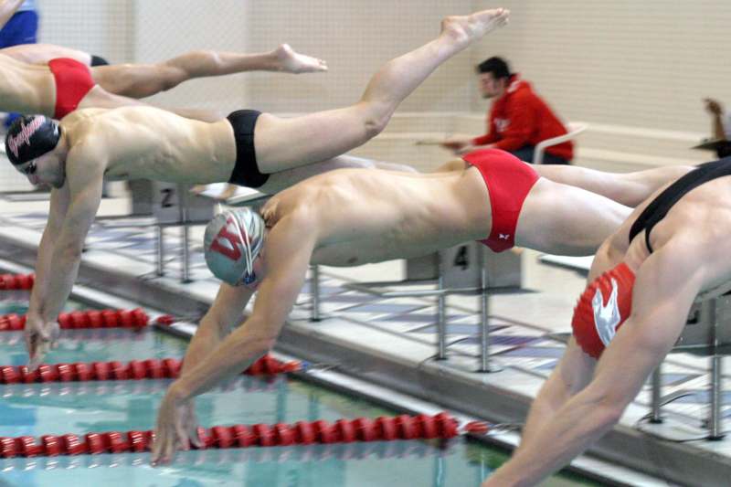 a group of swimmers diving into a pool
