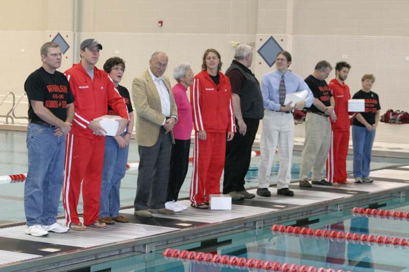 a group of people standing next to a swimming pool