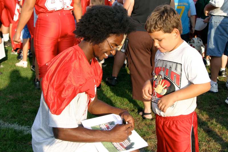 a man signing a book with a boy