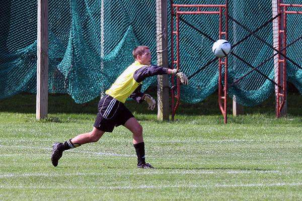 a man in a yellow shirt kicking a football ball