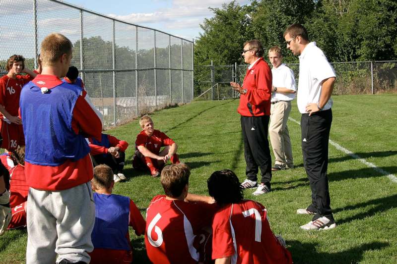 a group of men talking to a football team