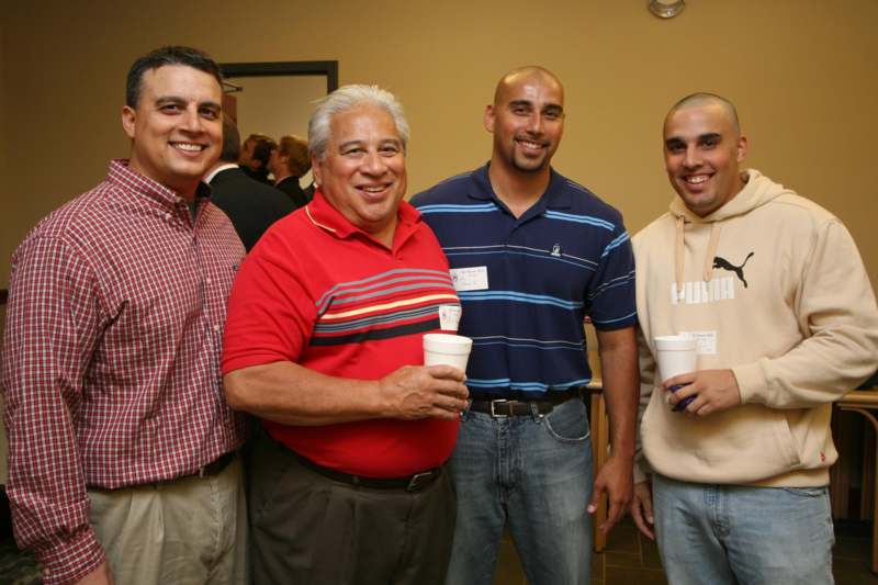 a group of men smiling and holding cups