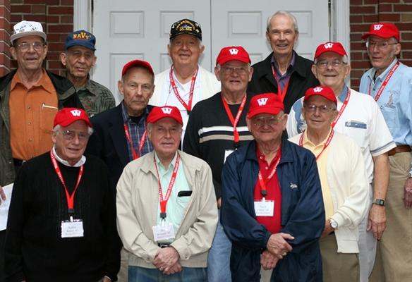 a group of older men wearing red hats