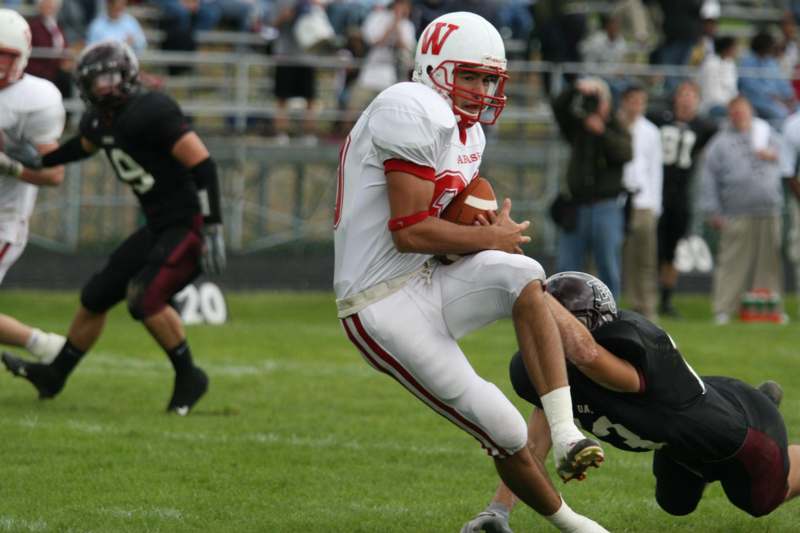 a football player in a white uniform running with a football in the back