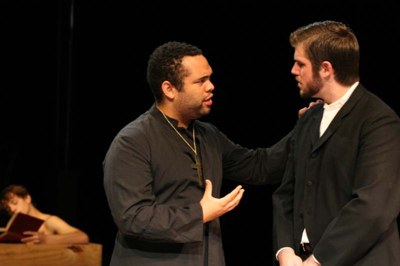 a man in a black robe talking to another man