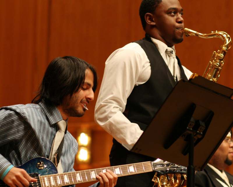a man playing a guitar and a man playing a saxophone