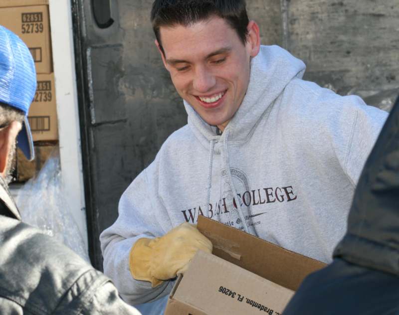 a man wearing gloves and a grey sweatshirt holding a box