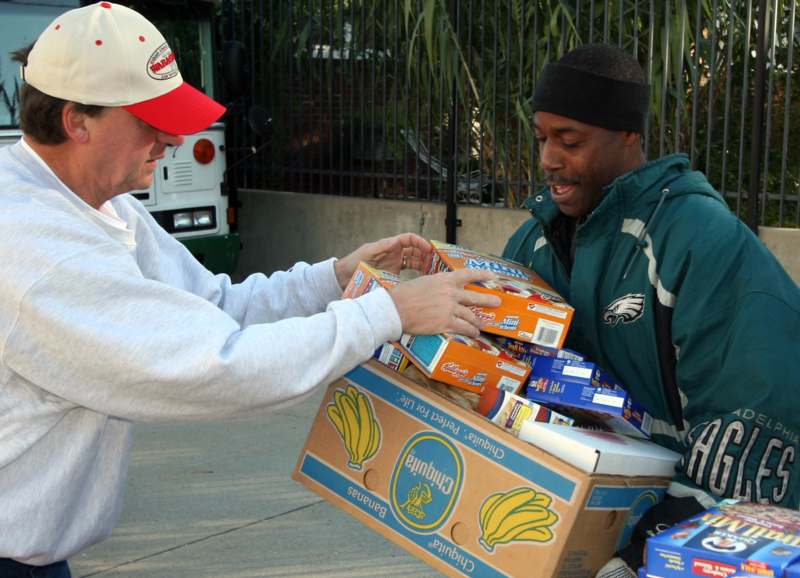 a man handing a box of food to another man