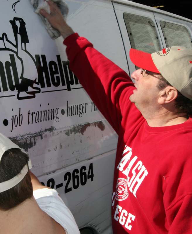 a man in red shirt and cap cleaning a van