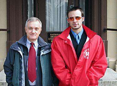 a man in a red coat and tie standing next to a man in a red coat and tie