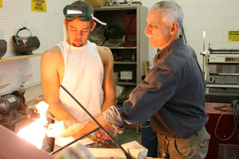 a man standing next to a man in a welding mask