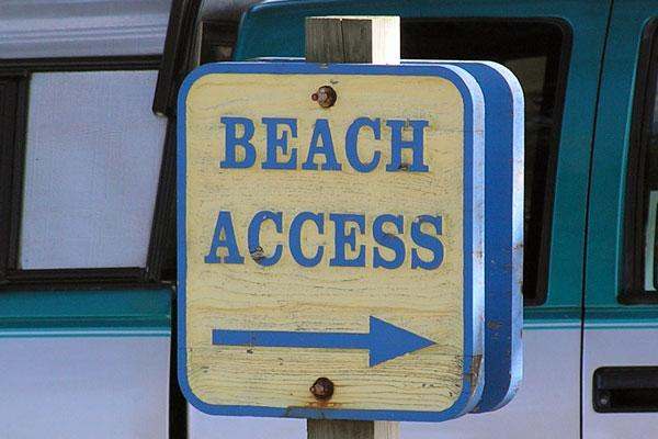 a sign with a arrow pointing to the beach access