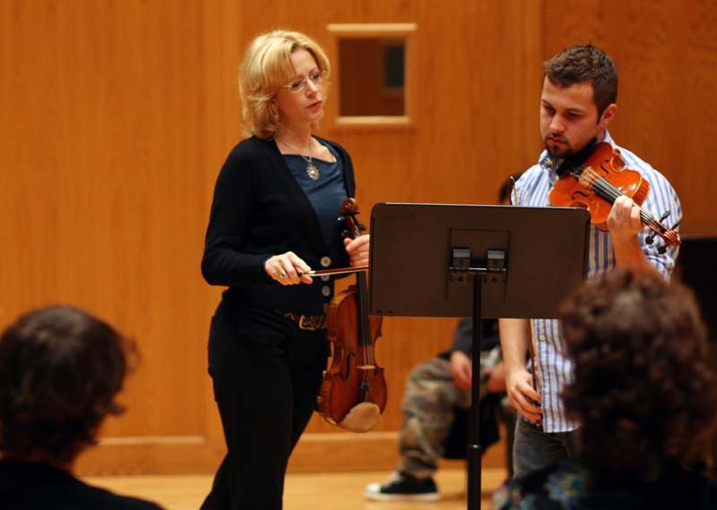 a woman holding a violin and a man standing in front of a crowd