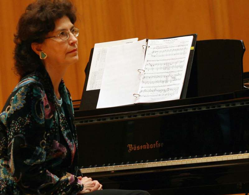 a woman sitting next to a piano