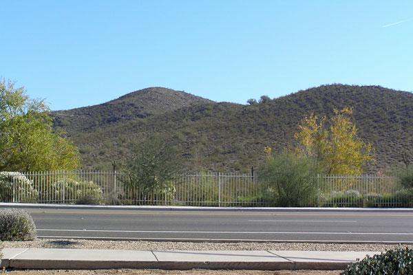 a road with a fence and mountains in the background