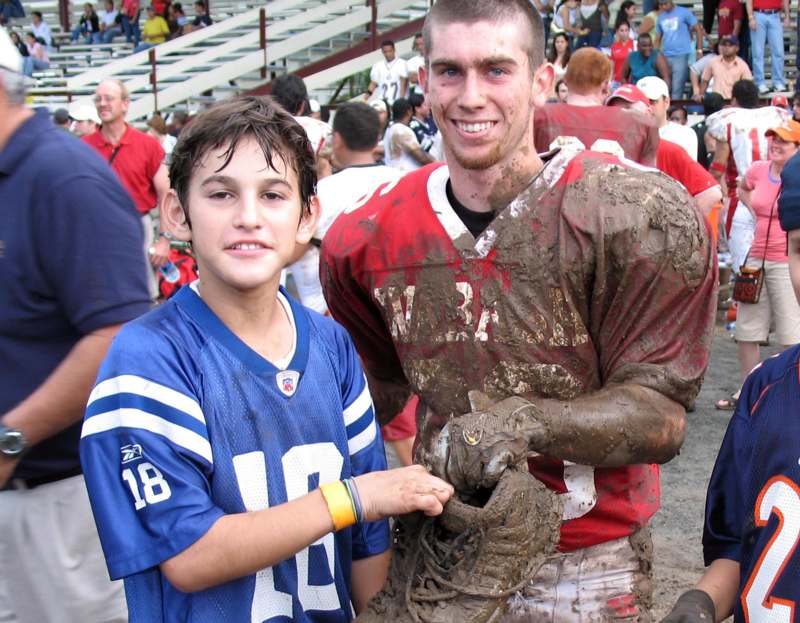 a man holding a football jersey with a boy in the background