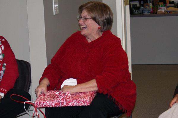 a woman in a red sweater opening a present
