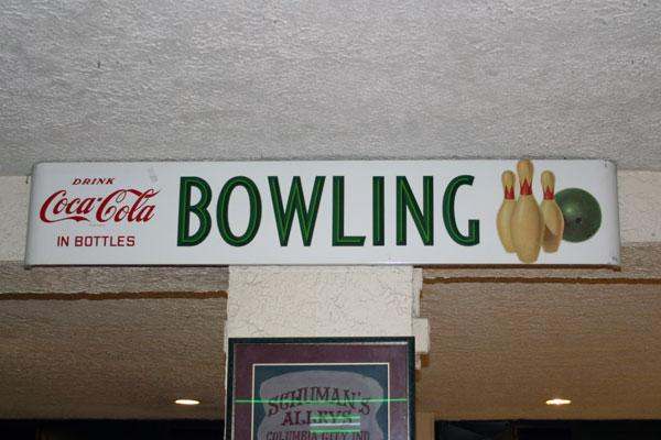 a sign with bowling pins and a coca cola logo