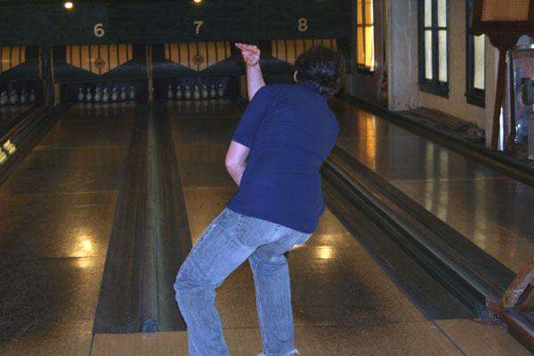 a person in a blue shirt throwing a bowling ball