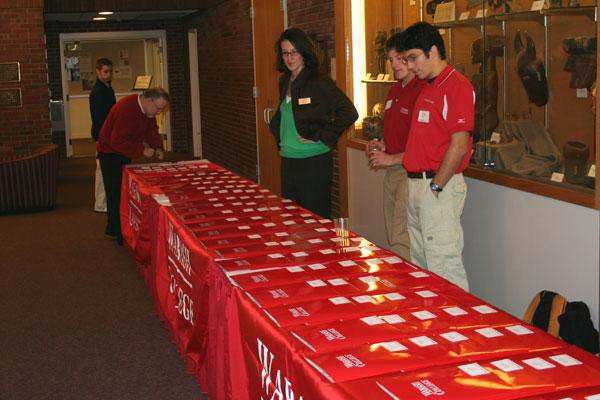 a group of people standing next to a table with red tablecloths