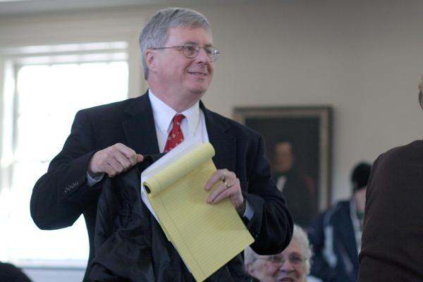 a man in a suit holding a yellow pad