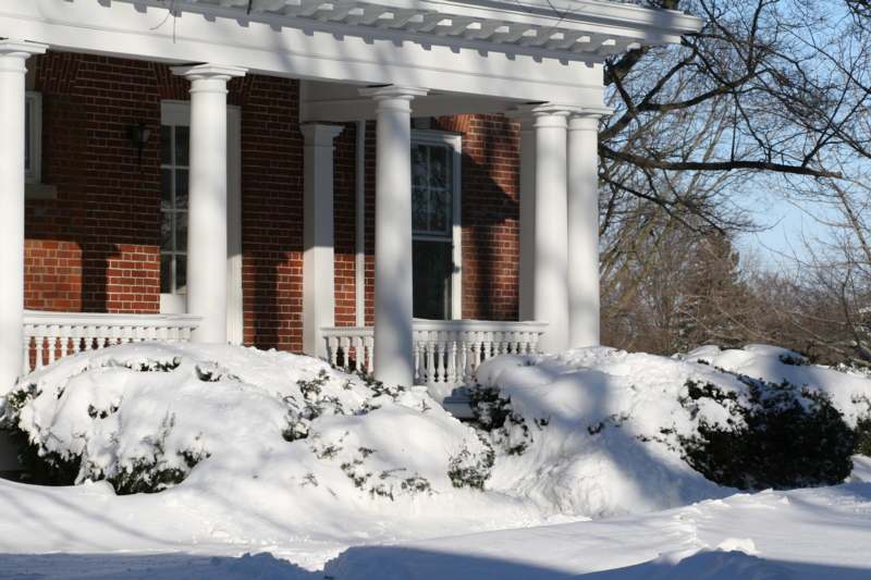 a snow covered yard with columns and bushes