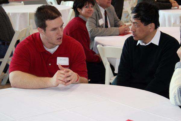 a man talking to a man at a round table