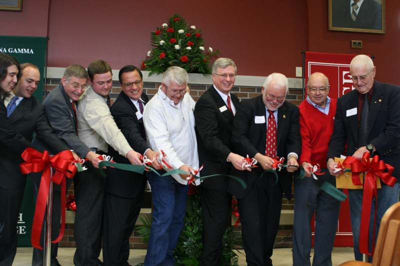 a group of men cutting a ribbon
