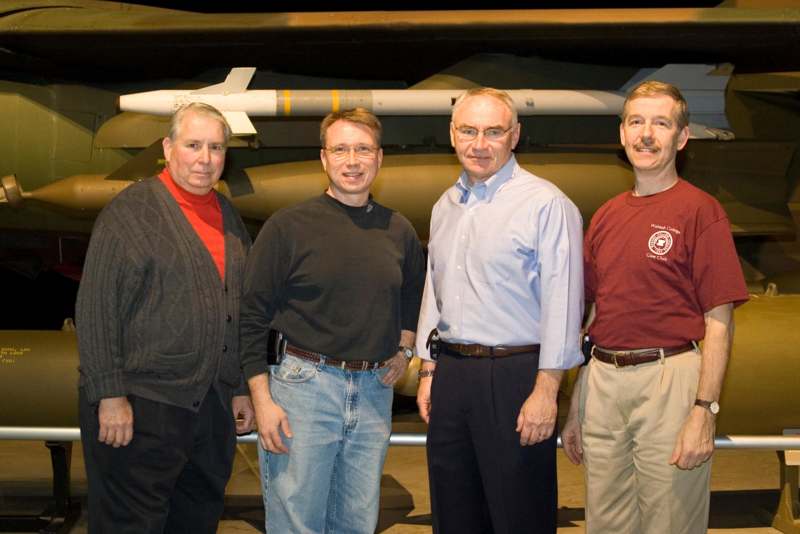 a group of men standing in front of a missile