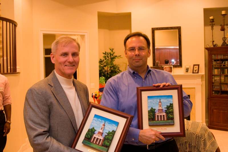 men holding framed pictures in a house