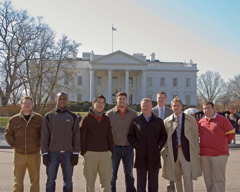 a group of men standing in front of a white house
