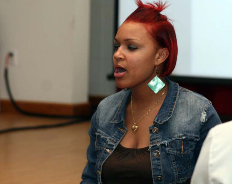 a woman with red hair wearing a denim jacket and a blue earring