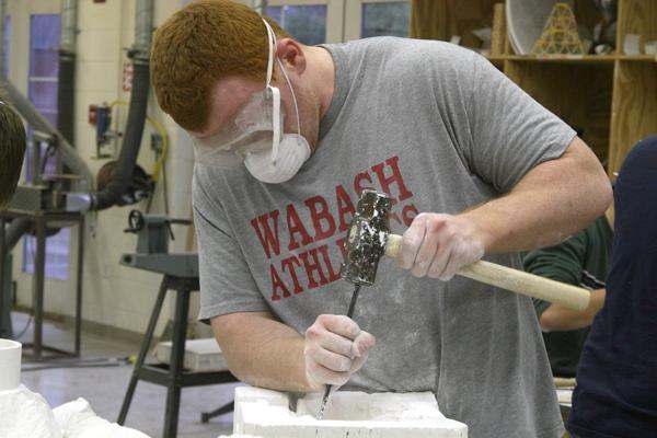 a man using a hammer to drill a sculpture
