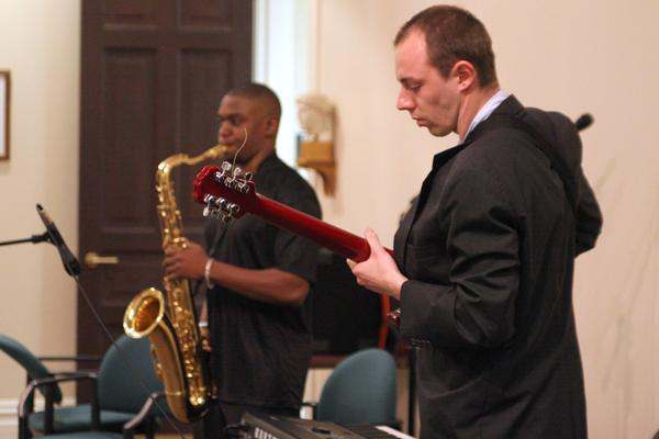 a man holding a guitar and a saxophone