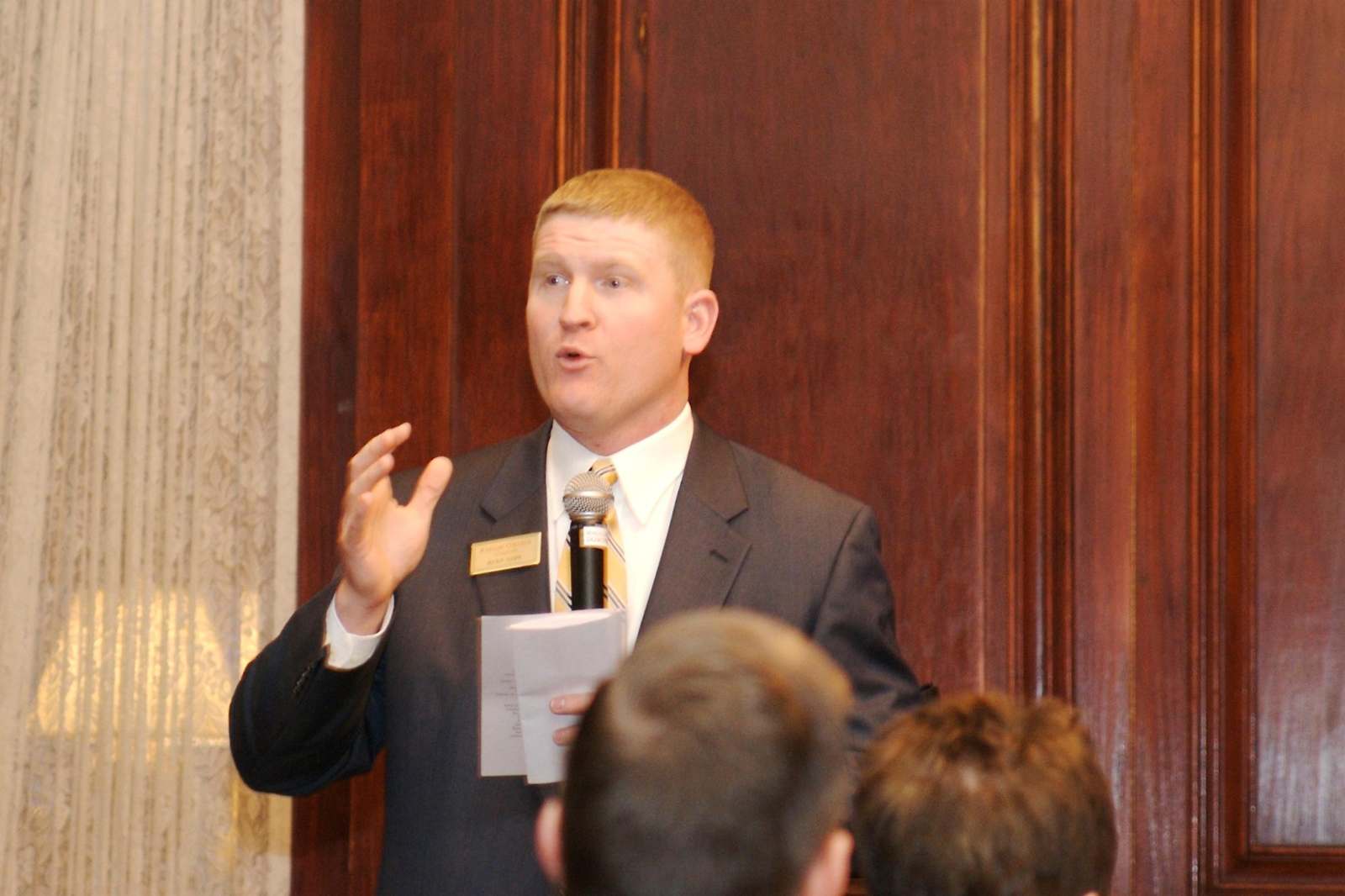 a man in a suit speaking to a group of people