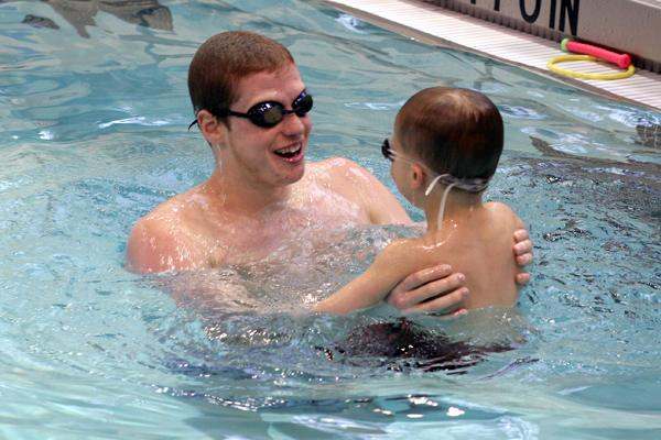 a man holding a child in a pool