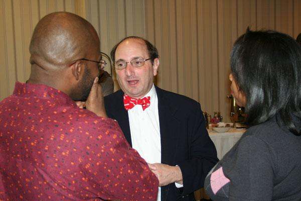 a man in a suit and bow tie talking to a group of people