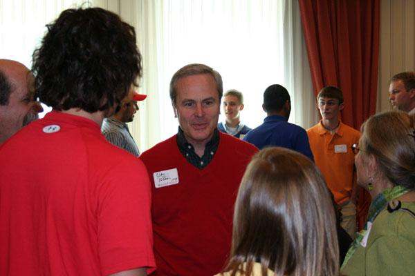 a man in a red shirt talking to a group of people