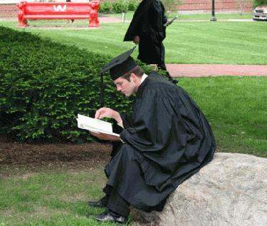 a man in a graduation gown reading a book