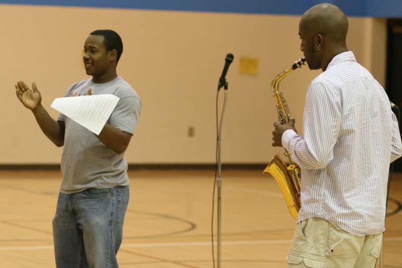 a man playing a saxophone next to another man