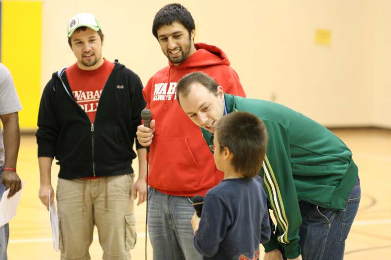 a group of men standing around a boy holding a microphone