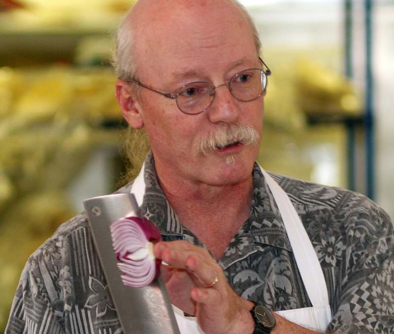 a man with a mustache and a white apron holding a knife