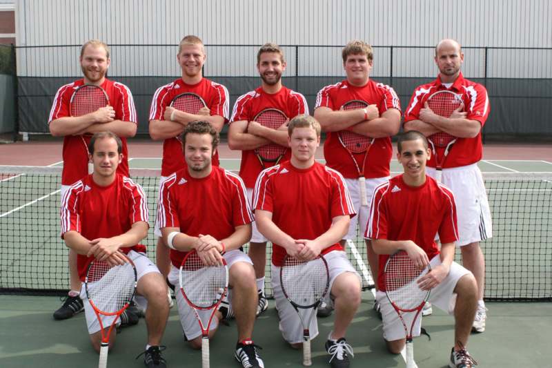 a group of men wearing red shirts and holding tennis rackets