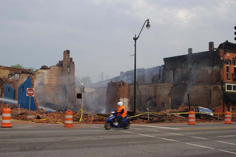 a man on a motorcycle in front of a destroyed building
