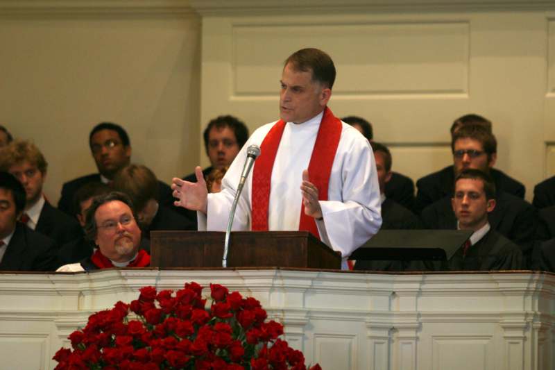a man in white robe and red scarf speaking at a podium