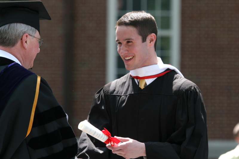 a man in a graduation gown smiling