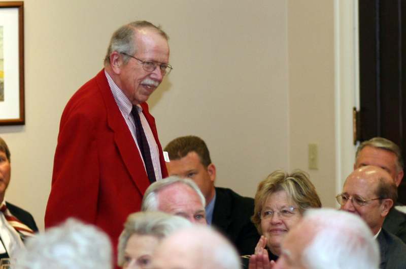 a man in a red suit standing in front of a crowd
